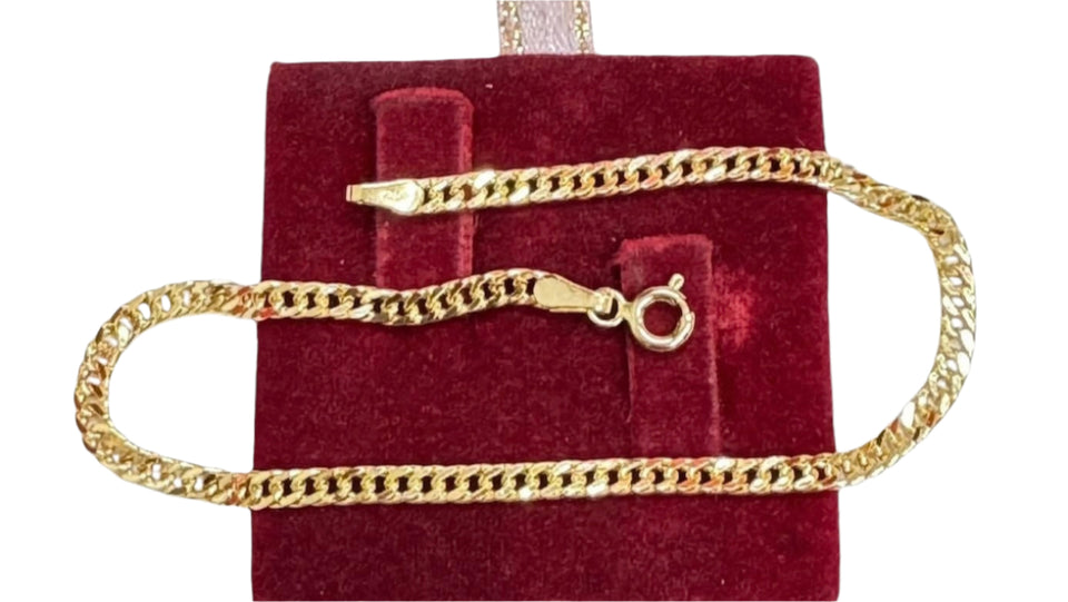 An 18K gold-colored bracelet displayed on a red velvet surface, with the clasp fastener visible.